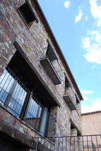 Detalle de la fachada trasera de la casa rural La Fuente Gorda: construcción en piedra, madera y forja.